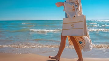 Una persona caminando por la playa con una toalla y una bolsa.