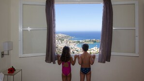 Two children standing by a window with a view of a coastal town. - Bellair Village (Malevizi)