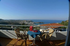 A balcony with wicker chairs, a table with a blue tablecloth, and a red house-shaped decoration. - Bellair Village (Malevizi)