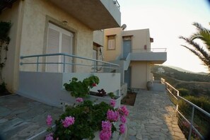 A two-story building with a balcony, stone flooring, and potted plants. - Bellair Village (Malevizi)