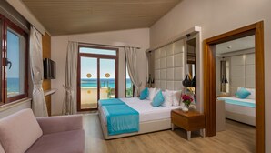 A modern hotel room with a large bed, a sofa, a wooden floor, a balcony with a view of the sea, and a mirror. - Bella Resort & Spa - All Inclusive (Manavgat)