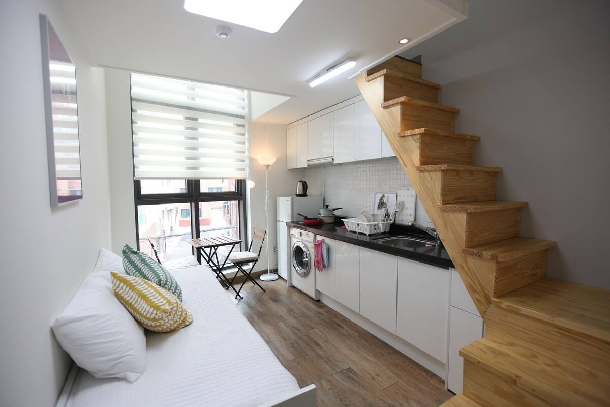 Una cocina compacta con muebles de madera, lavadora y zona de comedor con mesa y sillas.