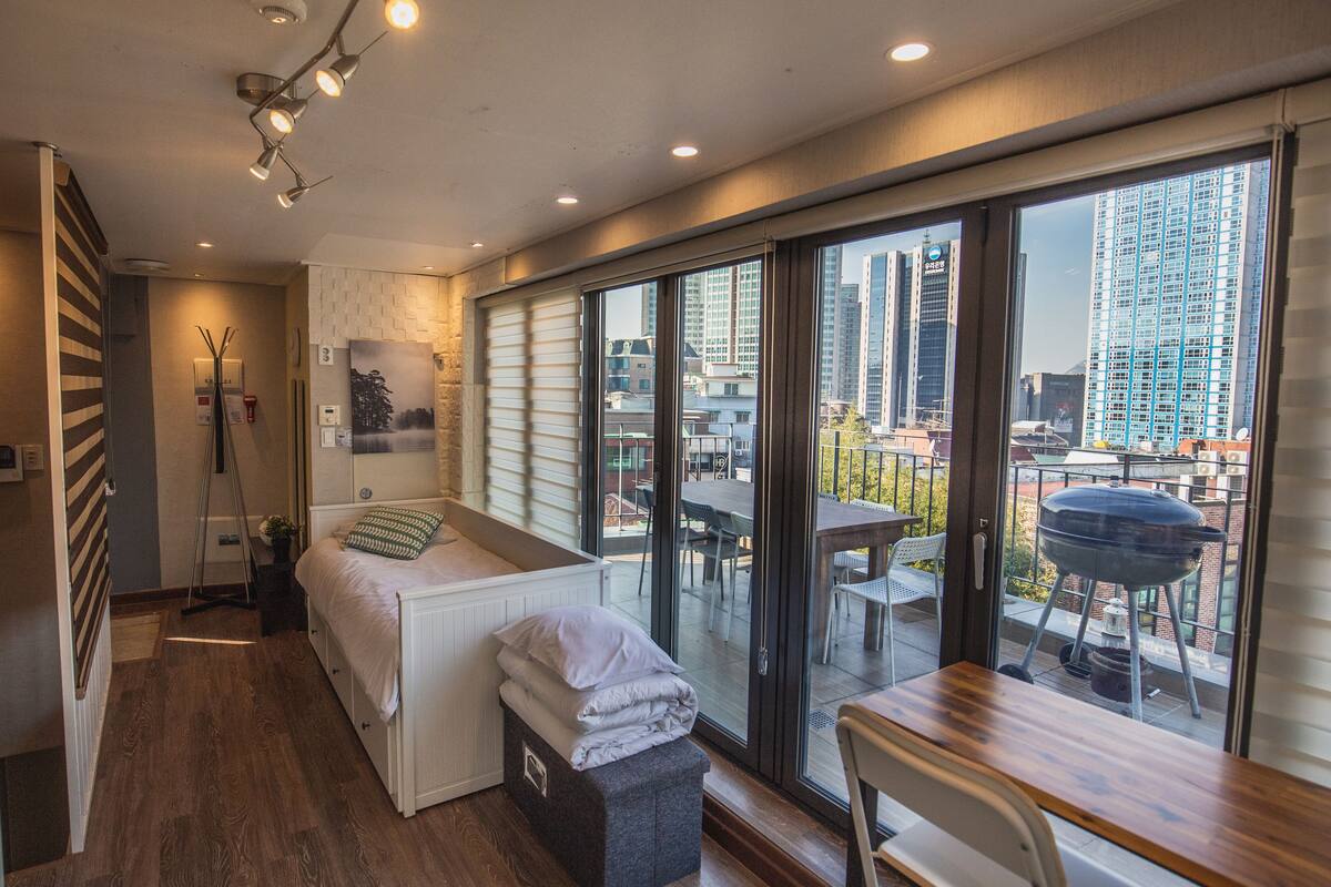 Un dormitorio moderno con un amplio ventanal corredera que da a un balcón exterior.