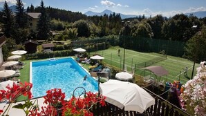 Una piscina amb una pista de tennis i vista a la muntanya.
