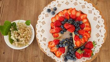 Una tarta de frutas redonda sobre una mesa de madera con un mantel de encaje.