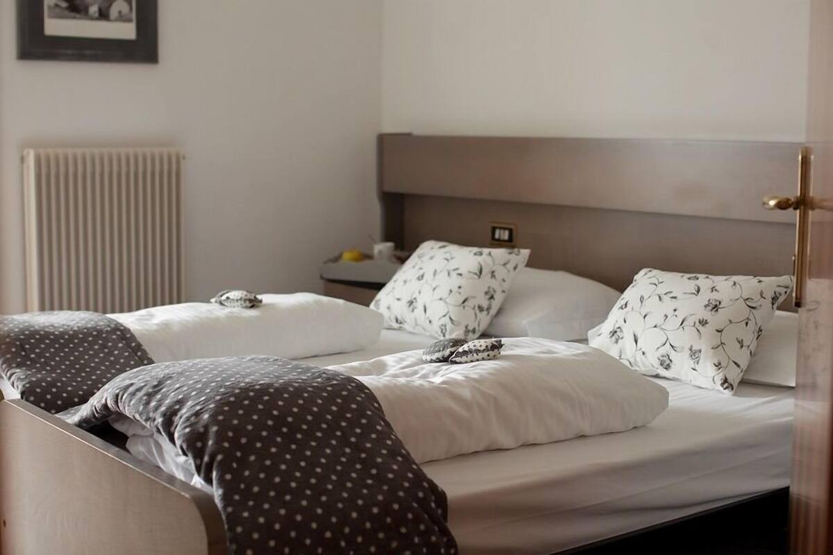 A double bed with a headboard, two pillows, and a blanket.