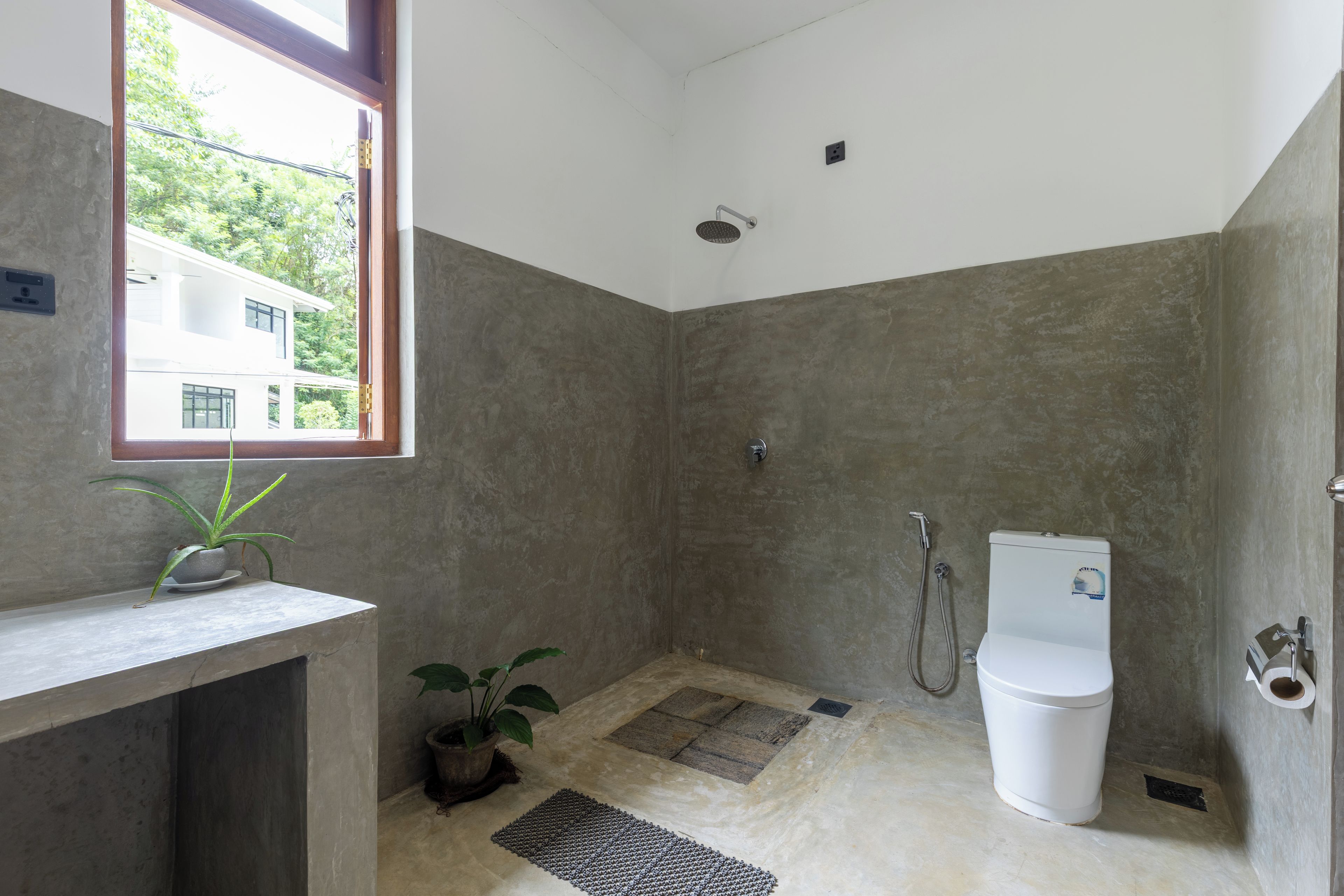 A bathroom with a shower, toilet, and a window with a view of a building outside.