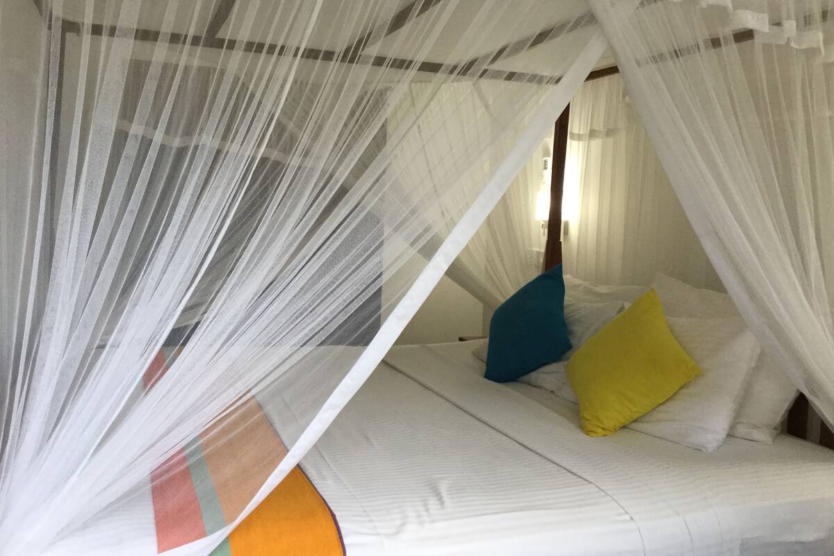 A bed with a white canopy and colorful pillows.
