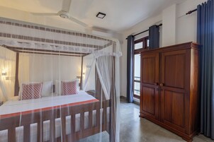Quarto com cama de dossel, guarda-roupa de madeira e janela com cortinas.