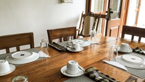 A dining table set with white plates, cups, and cutlery, surrounded by wooden chairs. - Hanthana House (Kandy)