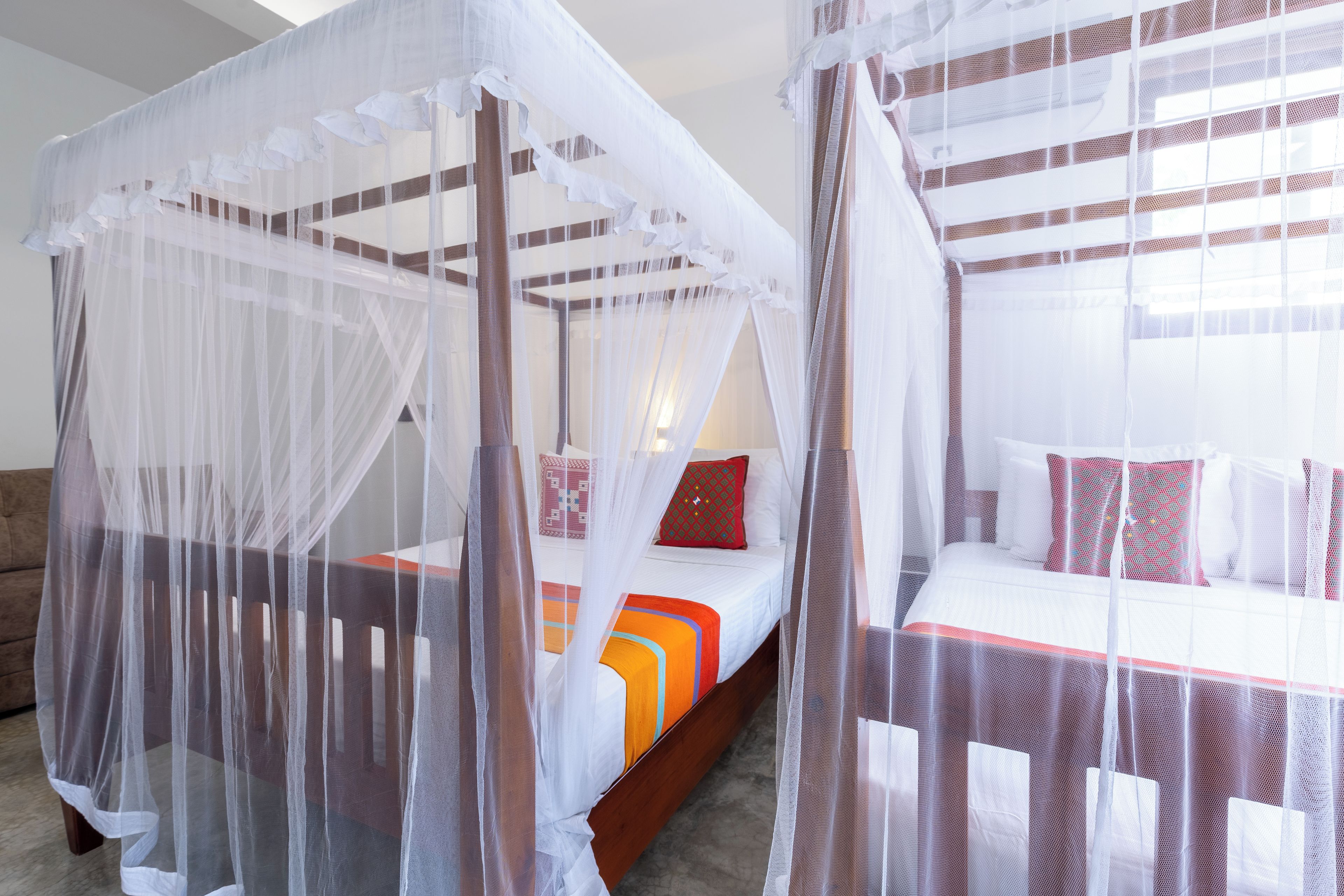 Une chambre avec deux lits, chacun étant agrémenté d’un couvre-lit à baldaquin et de coussins.