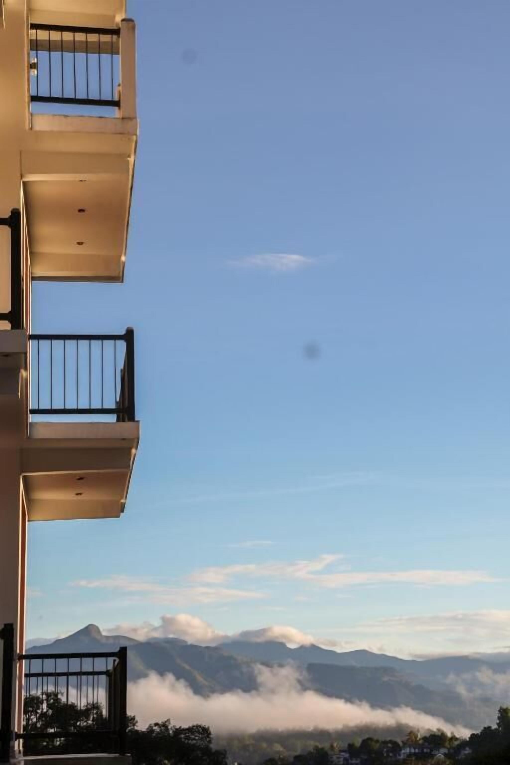A building with multiple balconies and a view of mountains and clouds.