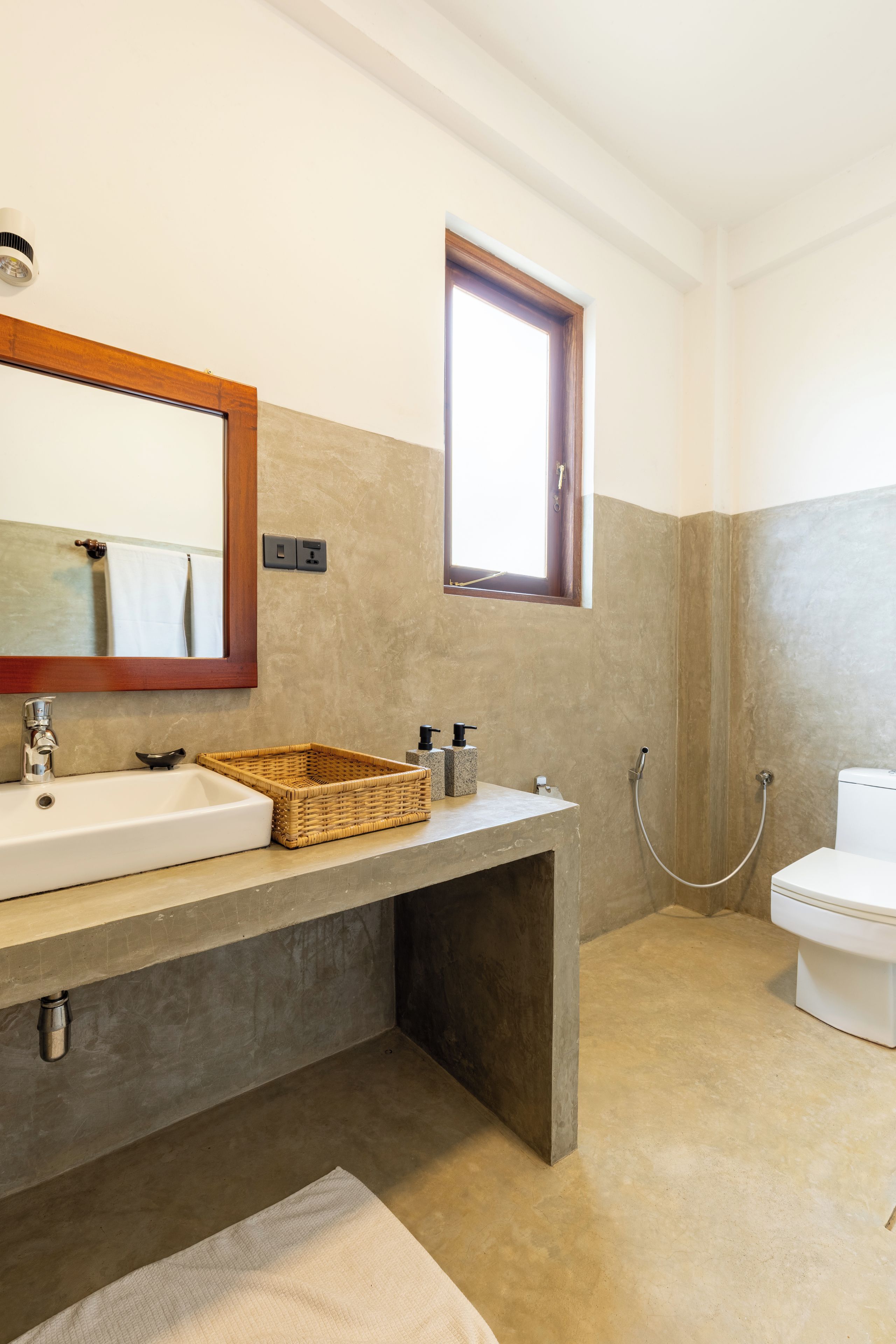 Ein Badezimmer mit einem großen Spiegel, einem Waschbecken, einem Fenster und einer Toilette.