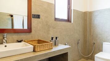 Ein Badezimmer mit einem großen Spiegel, einem Waschbecken, einem Fenster und einer Toilette.