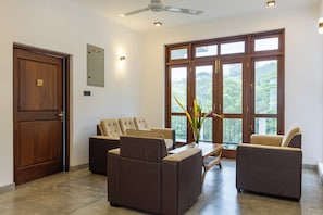 A spacious room with a large window, a ceiling fan, and a wooden door.