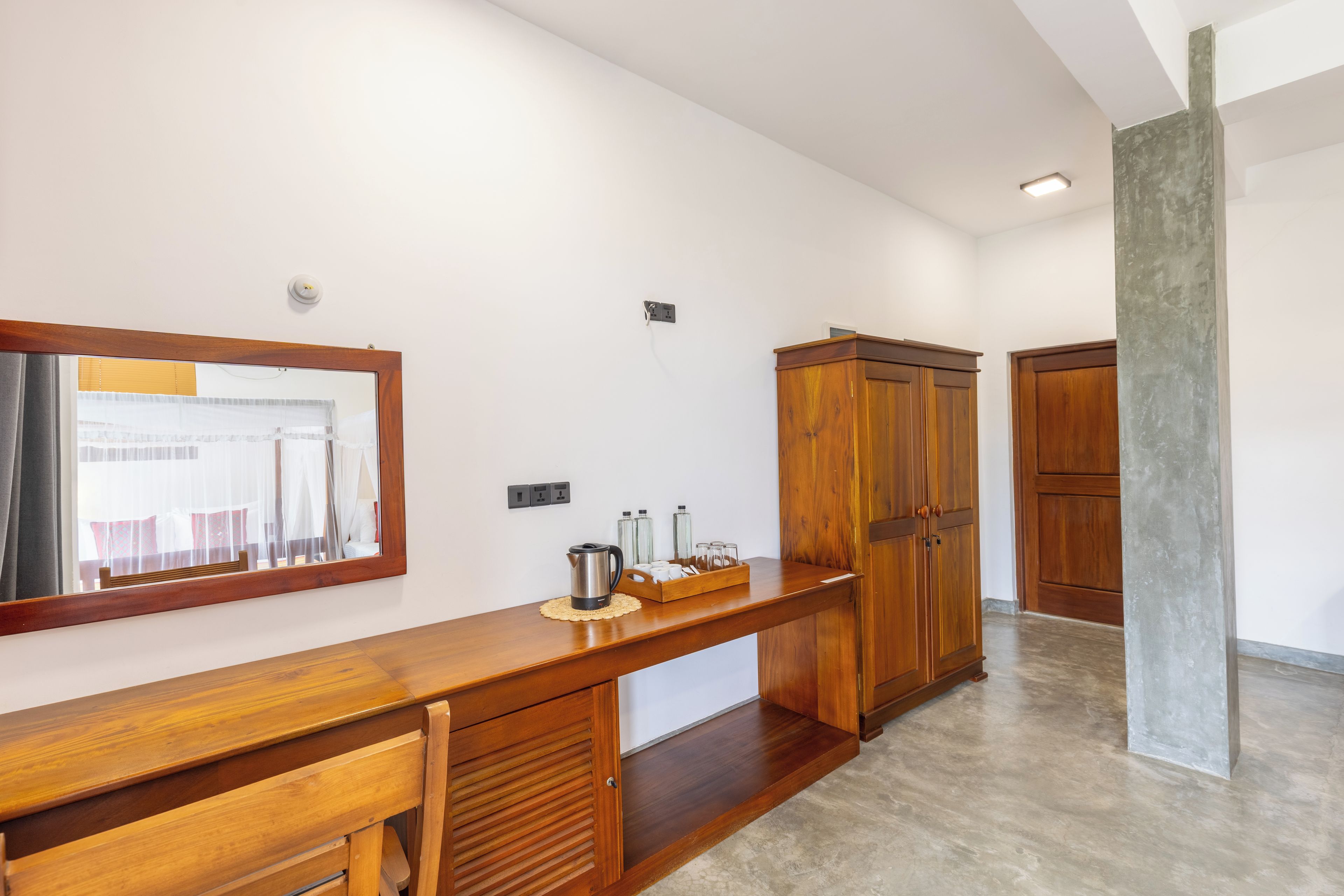 Une chambre d’hôtel avec un bureau en bois, un miroir, une armoire et une vue sur l’extérieur.