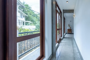 A corridor with large windows, a wooden door, and a statue.