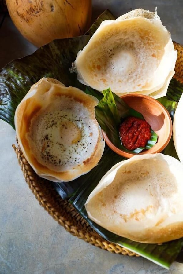A traditional South Indian dish, possibly idli, served on banana leaves with a side of chutney. - Hanthana House (Kandy)
