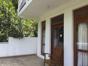 A balcony with a wooden chair, white walls, and a window with a curtain. - Hanthana House (Kandy)