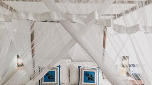 A bed with white linens and blue pillows, a canopy overhead, and a view of the outside. - Hanthana House (Kandy)