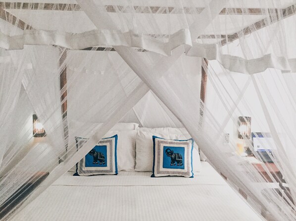 A bed with white linens and blue pillows, a canopy overhead, and a view of the outside. - Hanthana House (Kandy)