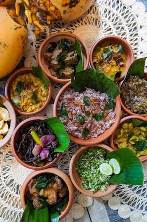 A variety of dishes served in terracotta bowls on a woven tablecloth. - Hanthana House (Kandy)