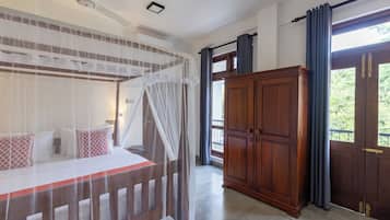 A bedroom with a four-poster bed, a wooden wardrobe, and a balcony with curtains.