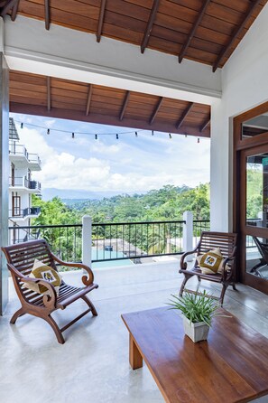 A balcony with two wooden chairs, a table, and a potted plant. - Hanthana House (Kandy)