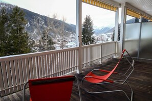 A balcony with a view of snow-covered mountains and a town below. - Youth Hostel Davos Youthpalace (Davos)