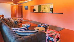 Un vestíbulo moderno con un sofá de cuero largo, otomanas coloridas, un mostrador de recepción y una pared con diseño.