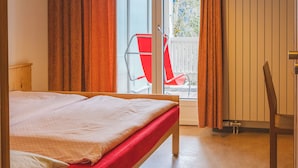 Un dormitorio con cama, ventana y vista a un balcón con una silla.