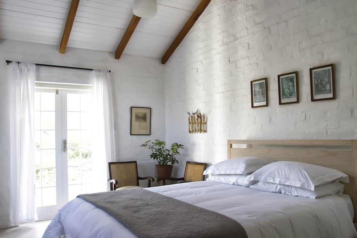 Ein Schlafzimmer mit einem Bett, einer Topfpflanze und einem Holz-Kopfteil.
