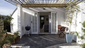 Un patio couvert avec une pergola, un barbecue et des sièges d’extérieur.
