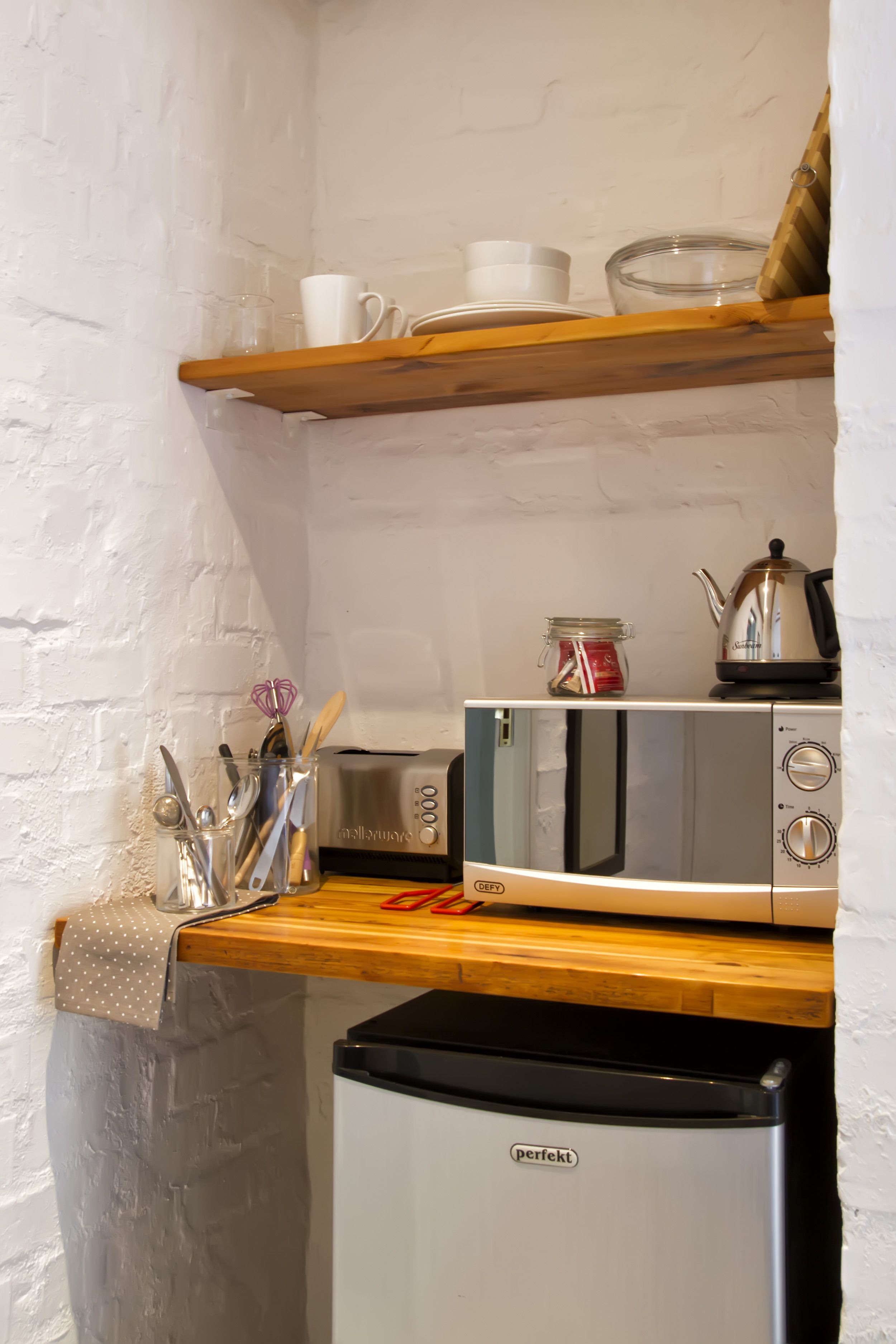 Une cuisine compacte équipée d’un four à micro-ondes, d’un grille-pain et d’un petit réfrigérateur.