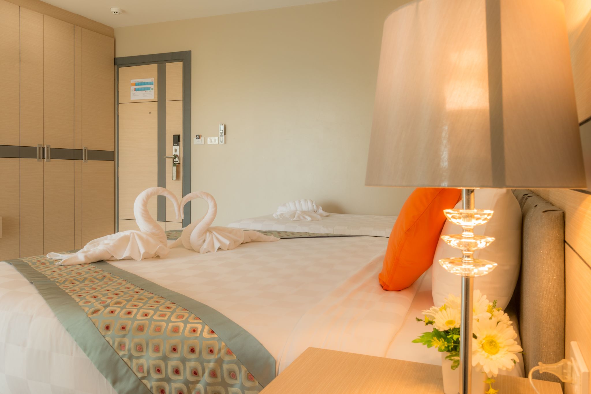 A hotel room with a bed, a nightstand, a lamp, and a door.