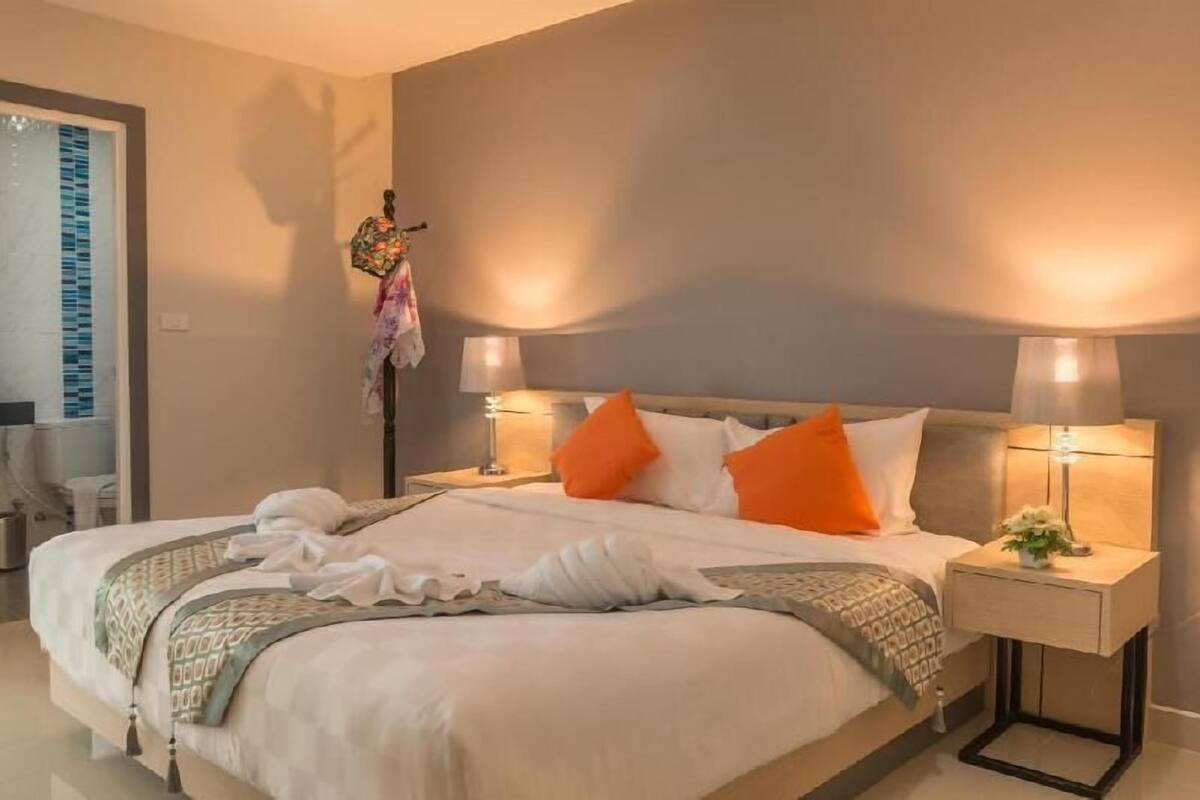 Una cama doble con dos mesitas de noche, una lámpara y un adorno en la mesita.