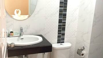 Une salle de bain avec un lavabo blanc, un comptoir noir et des toilettes sur lesquelles est posée une serviette blanche.