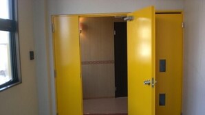 A yellow door with a red carpet leading to a room. - La Mer - Hostel (Osaka)