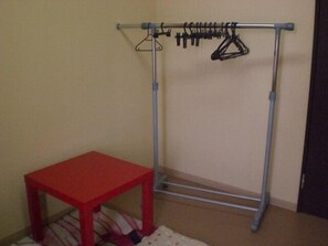 Una habitación con una mesa roja y un tendedero metálico apoyado en la pared.