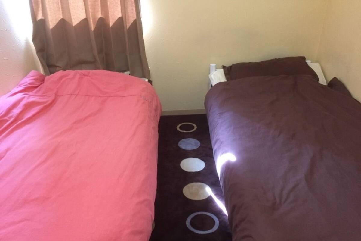 A room with two beds, one with a pink bedspread and the other with a brown bedspread.