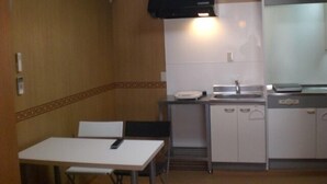 A compact kitchen with a white table, a small sink, and a microwave. - La Mer - Hostel (Osaka)