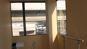 A small balcony with a view of a parking lot and buildings. - La Mer - Hostel (Osaka)