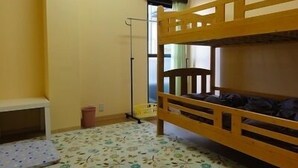 A bunk bed room with a small desk, a trash bin, and an air conditioning unit on the wall. - La Mer - Hostel (Osaka)