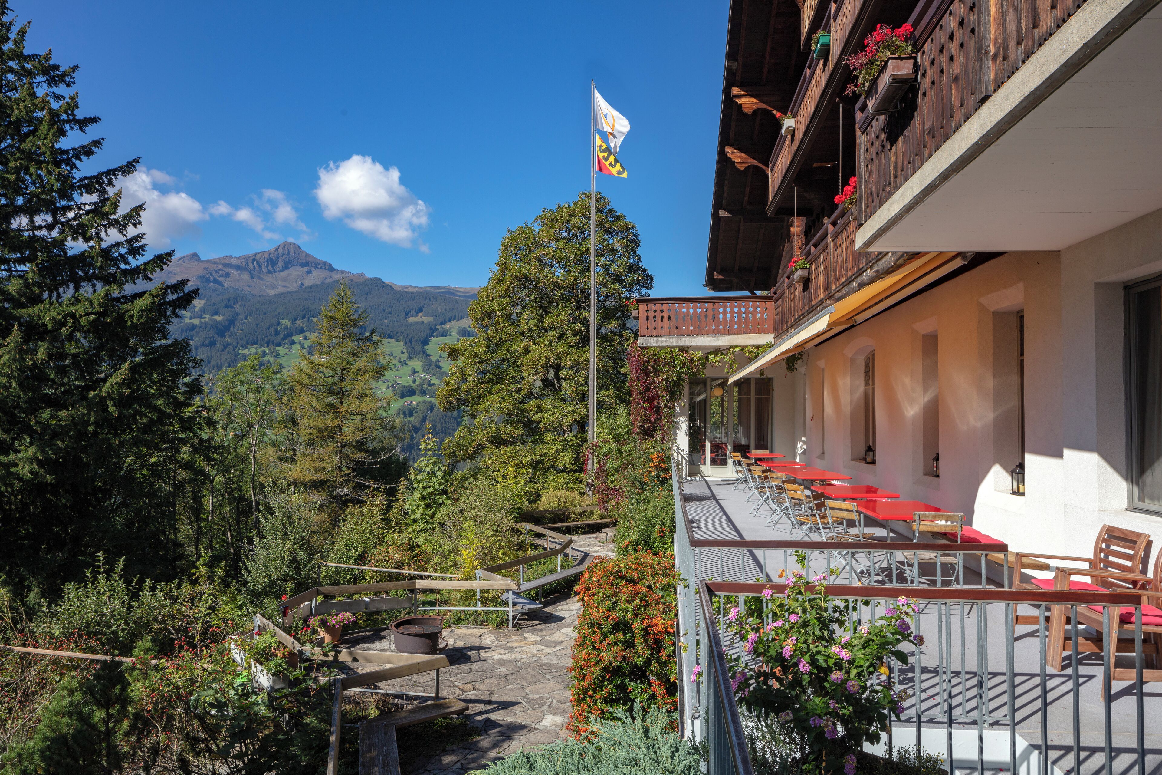 Vista de la montaña con una bandera, asientos exteriores y un edificio con balcones.
