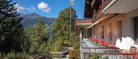 Vista de la montaña con una bandera, asientos exteriores y un edificio con balcones.