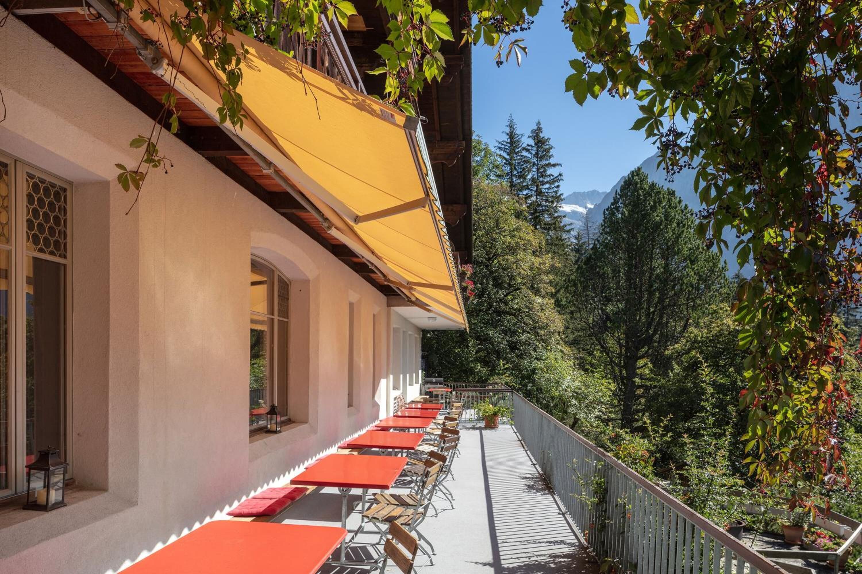 Une terrasse avec des sièges extérieurs, un balcon en bois et une vue sur les arbres et les montagnes.