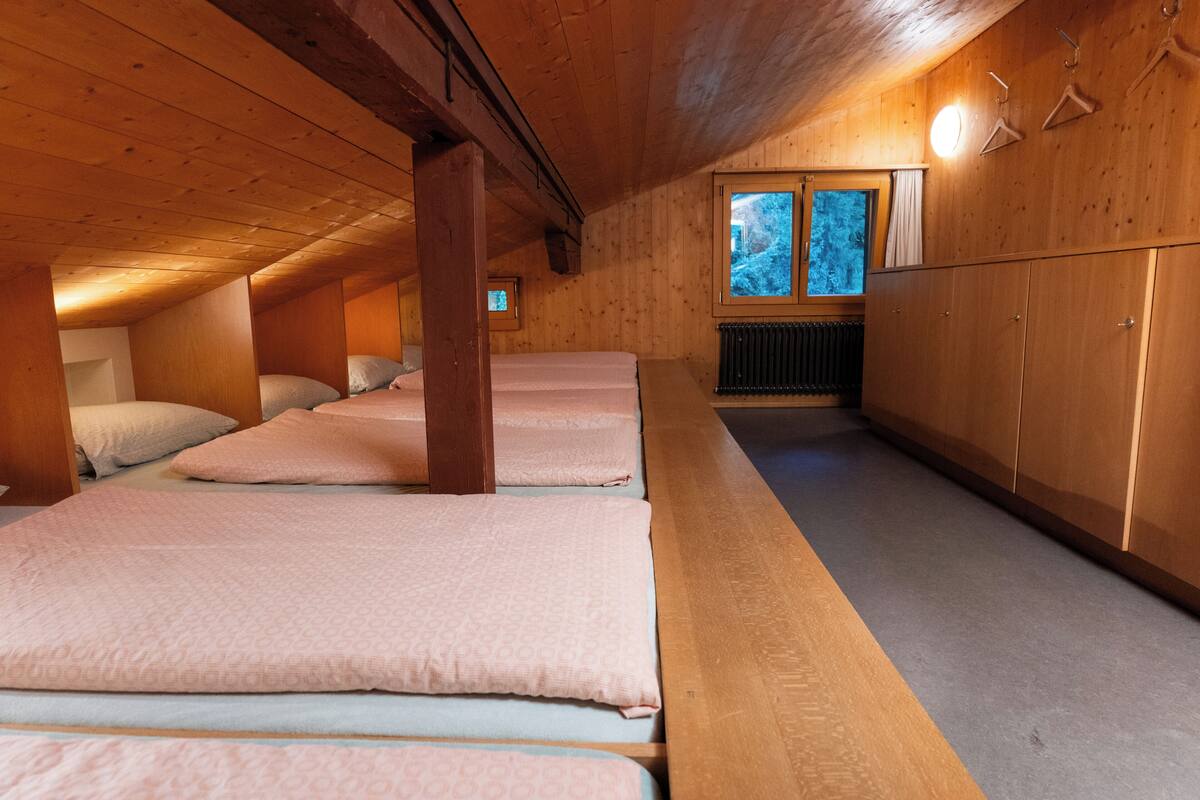 Ein Zimmer mit Holzbalken, Etagenbetten, einer Heizung und einem Fenster mit Blick.