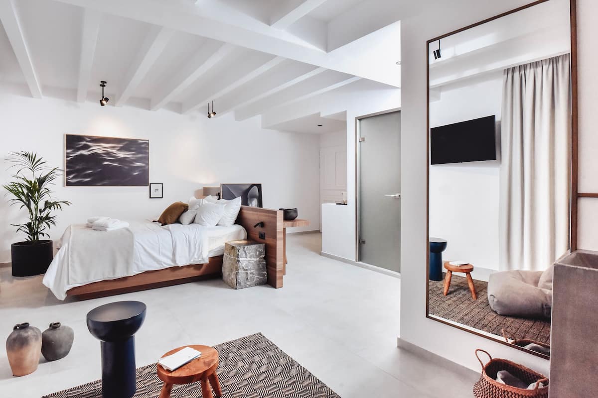 A modern bedroom with a bed, bedside table, and a large mirror.