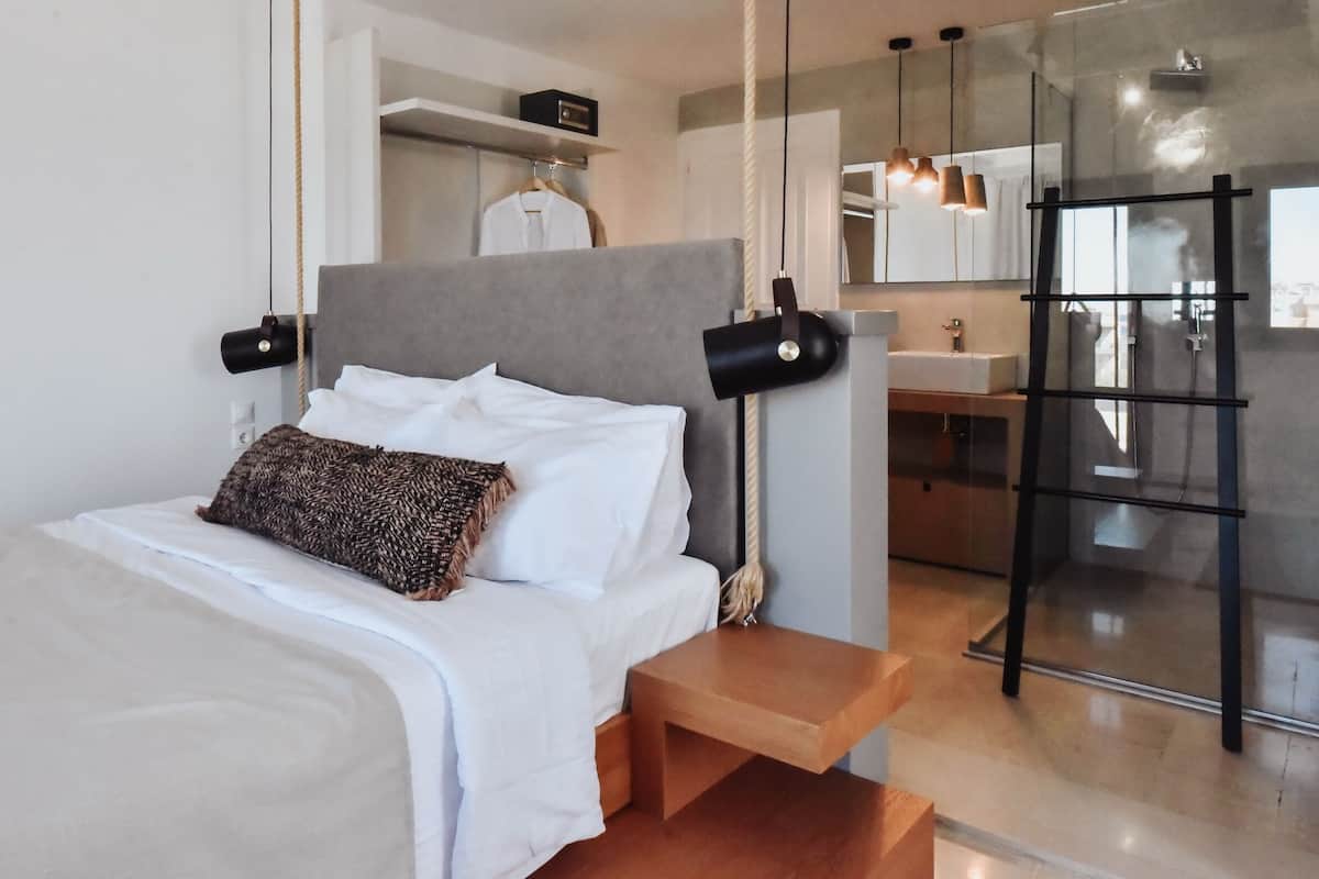 A modern hotel room with a bed, bedside table, and a view of the bathroom.