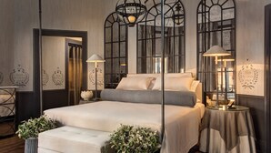 Een moderne slaapkamer met een groot bed, twee nachtkastjes en decoratieve wandlampen.